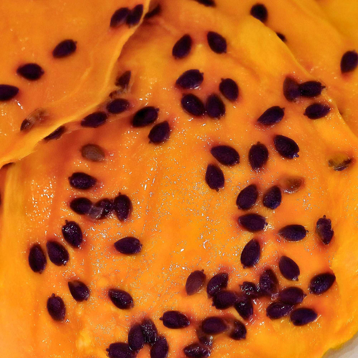 Close up of Australian dried mango layered with real passionfruit pulp and visible crunchy seeds.