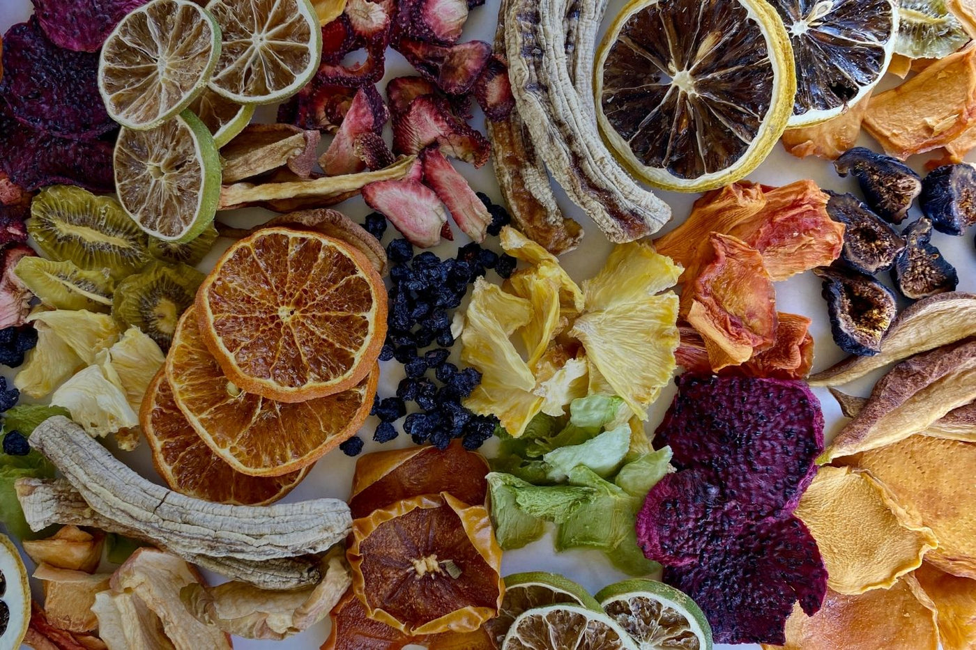 Top-down flatlay of assorted dried fruits including mango, orange, lemon, kiwi, pineapple, banana, fig and more. Healthy, no-sugar-added snacks by Tropical Harvest.