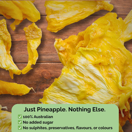 Dried pineapple slices from Tropical Harvest displayed on wood with text overlay: "Just Pineapple. Nothing Else." No added sugar, sulphites, or preservatives.