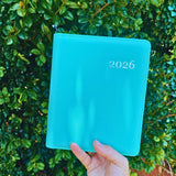 Front cover of aqua blue 2026 hardcover planner held in hand