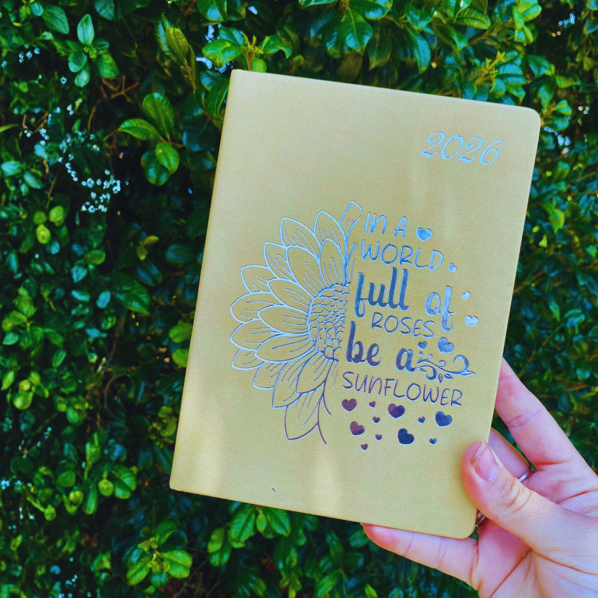 Close-up of 2026 diary with cream sunflower cover – In a world full of roses, be a sunflower