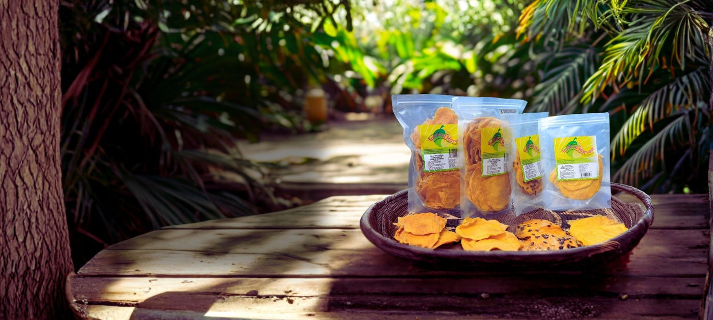 Australian dried mango range from Tropical Harvest including premium mango, standard mango, mango passionfruit and mango lime displayed on a wooden table in a tropical orchard.
