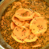 Australian dried mango slices dipped in fresh passionfruit pulp during mango passionfruit preparation.