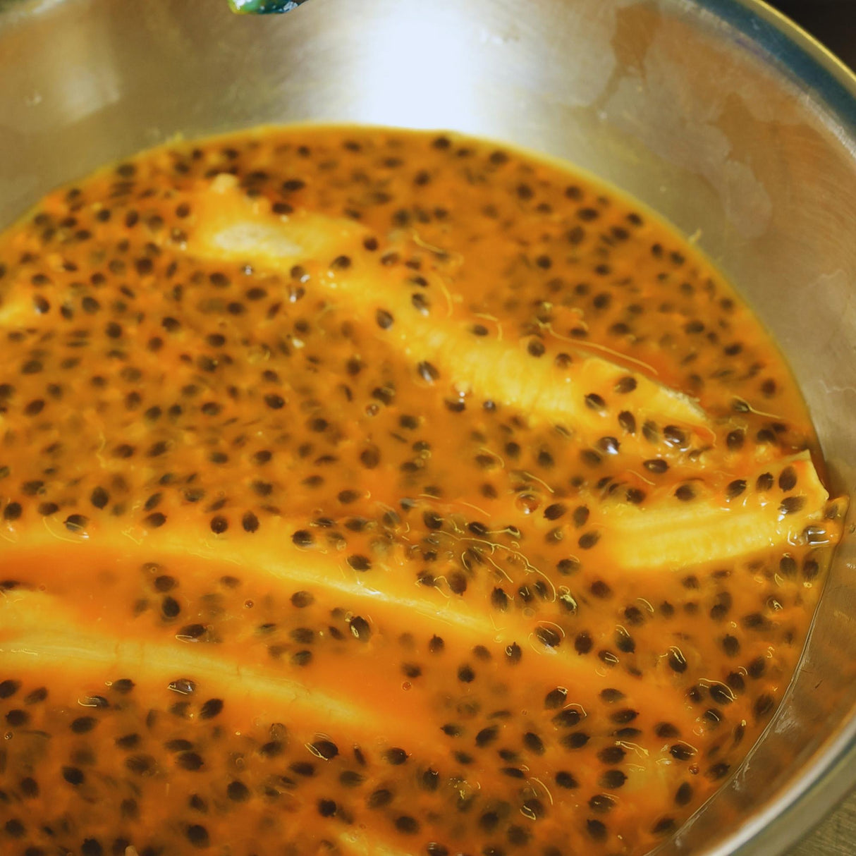 Banana slices soaking in passionfruit pulp during natural infusion process