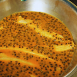 Banana slices soaking in passionfruit pulp during natural infusion process