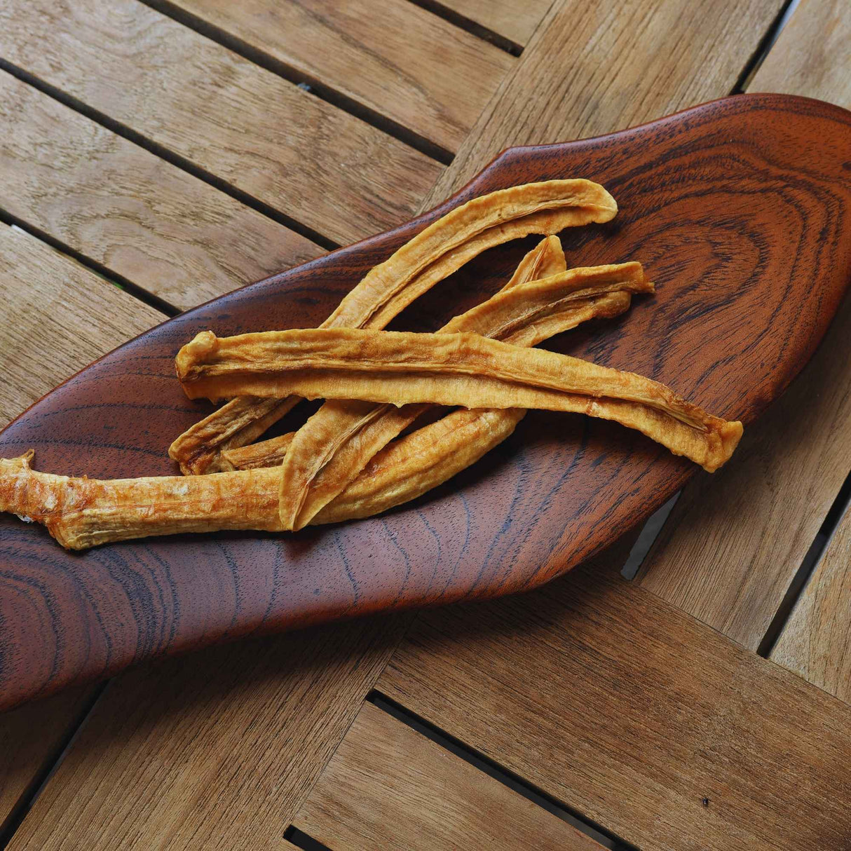 Australian dried banana with lime slices laid on a wooden board, showing natural colour and light citrus coating