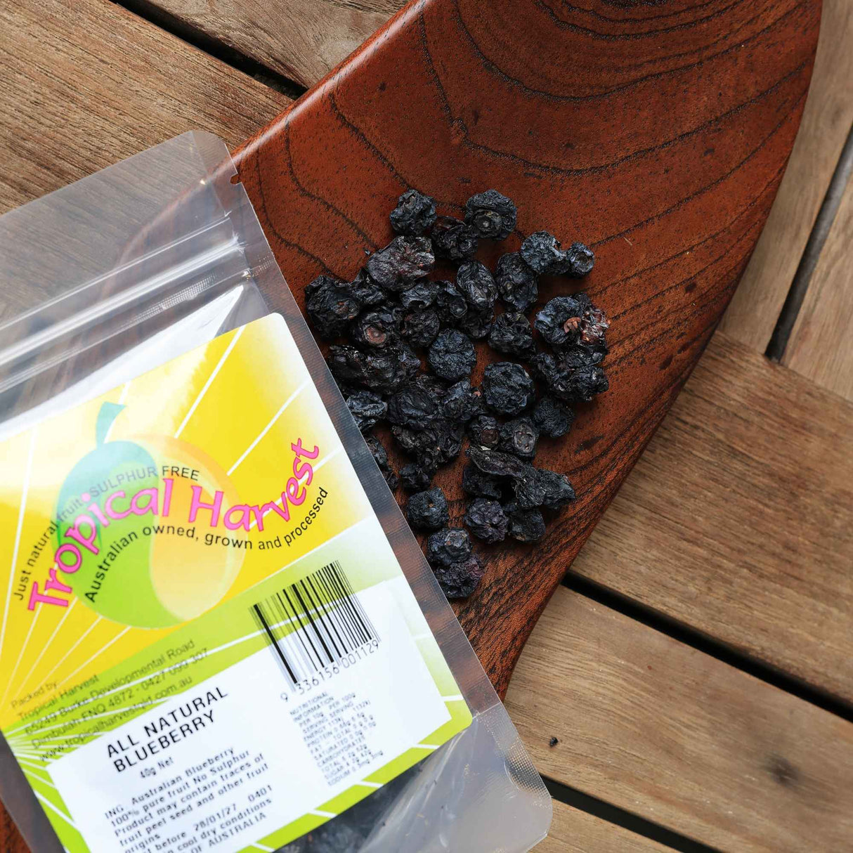 Dried blueberries displayed on wooden board with packaging showing natural product