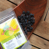 Dried blueberries displayed on wooden board with packaging showing natural product