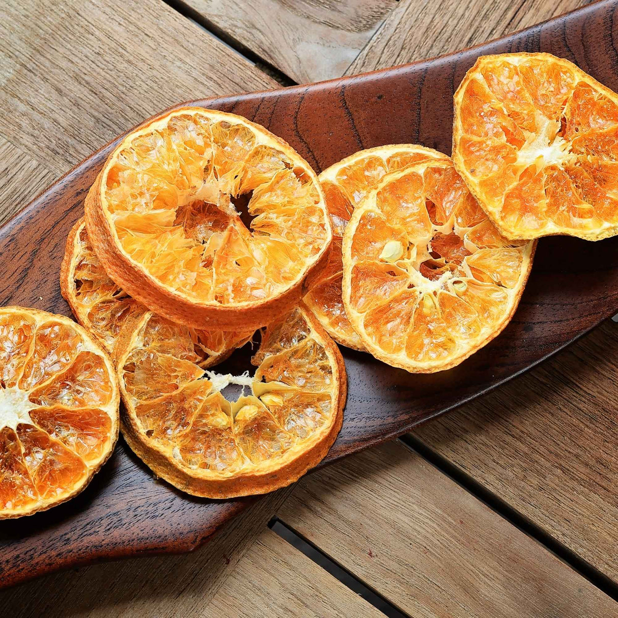Dried mandarin slices arranged on wooden board for natural food styling and serving