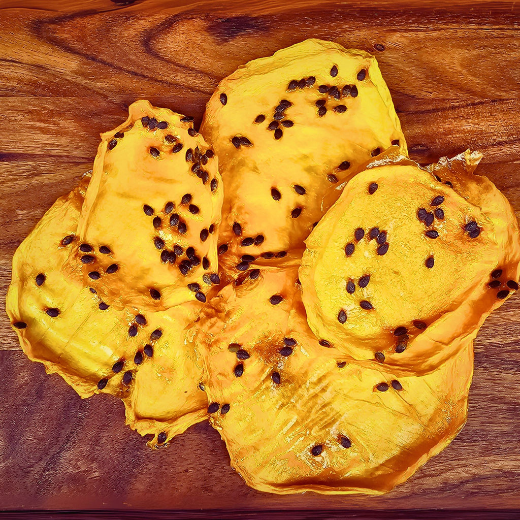 Close-up of dried mango fruit slices infused with passionfruit seeds, displayed on a wooden board to show chewy texture and natural dried finish.