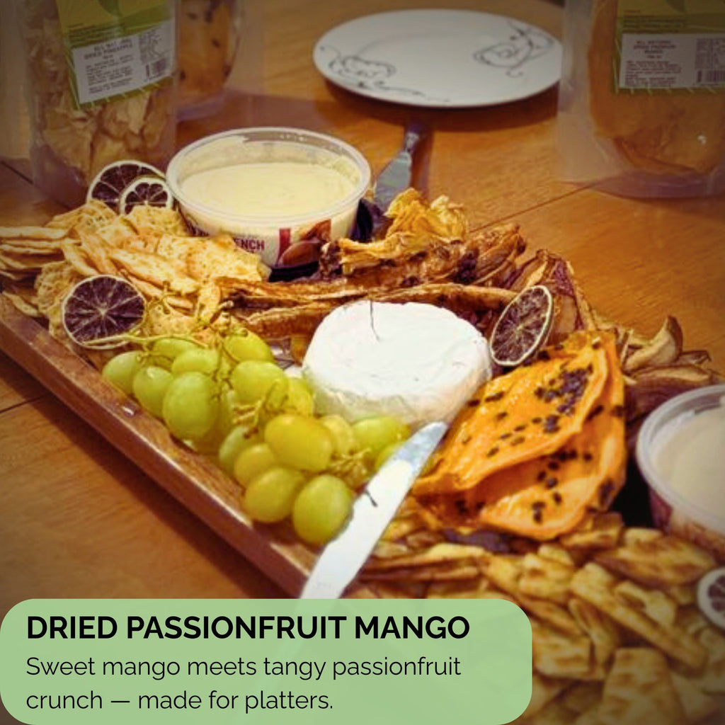 Slices of dried mango with passionfruit seeds featured on a wooden grazing board alongside grapes, cheese, dips, and crackers — ideal as a platter addition.
