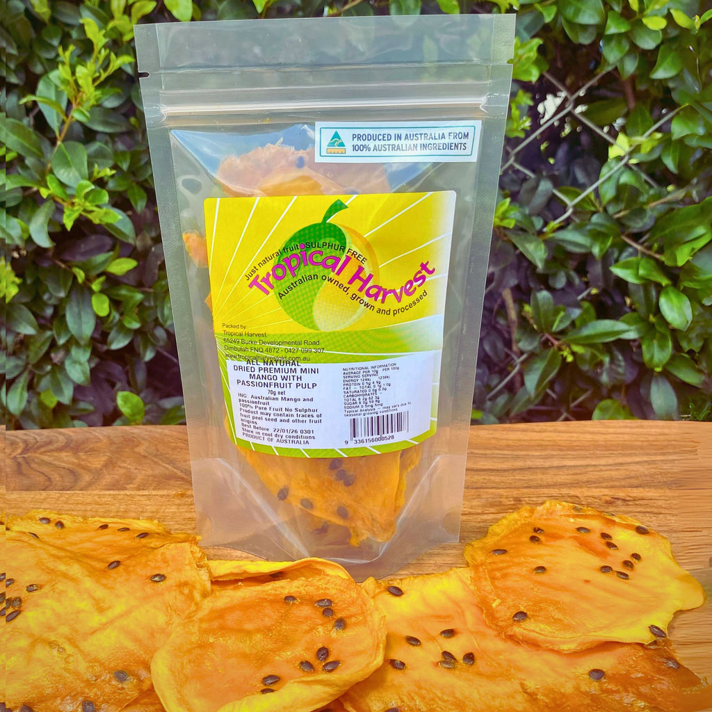Dried passionfruit mango 70g pack with visible product label showing sulphur-free, Australian-grown ingredients and resealable packaging. Large upright bag of dried mango infused with real passionfruit, with seed-speckled slices displayed in front on a wooden surface