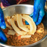 Hand preparing banana slices for dried banana passionfruit in a small batch process
