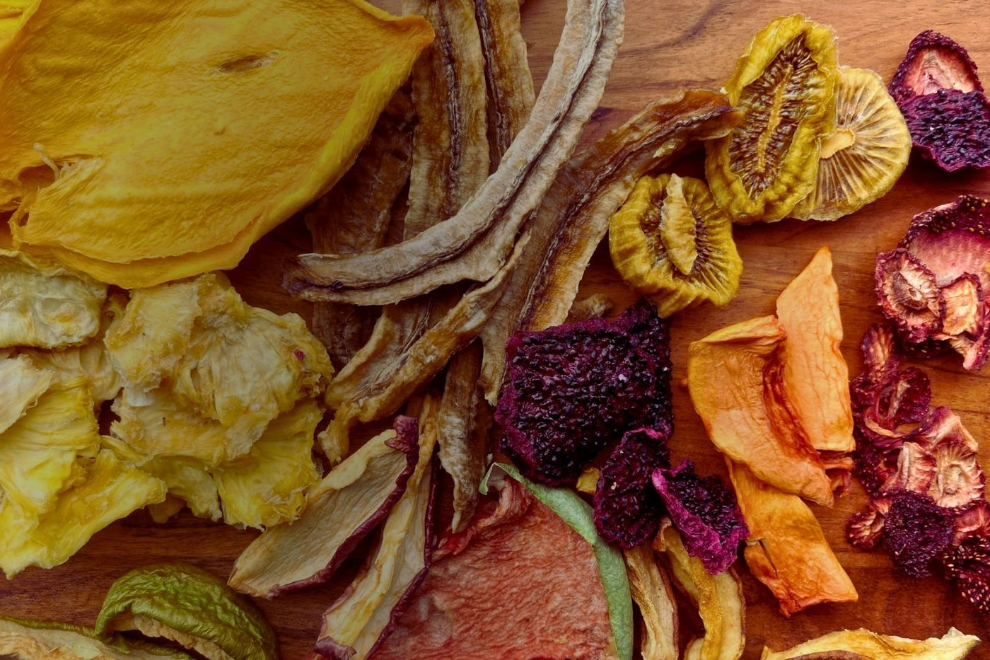 Assorted Australian dried fruits on a wooden board — featuring mango, kiwi, banana, dragon fruit, melon, and more in a vibrant, tropical mix