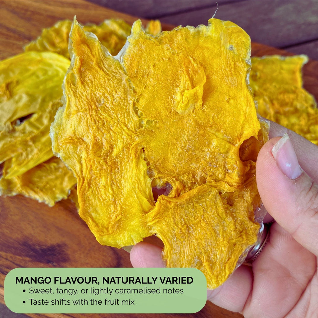 Close-up of Standard Australian Dried Mango slice in hand, showing bright golden colour. Text overlay reads “Mango Flavour, Naturally Varied – Sweet, tangy, or lightly caramelised notes. Taste shifts with the fruit mix