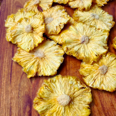 Close-up of Tropical Harvest dried pineapple flowers on a wooden board. Petal-like slices, naturally chewy, 100% Australian-grown fruit