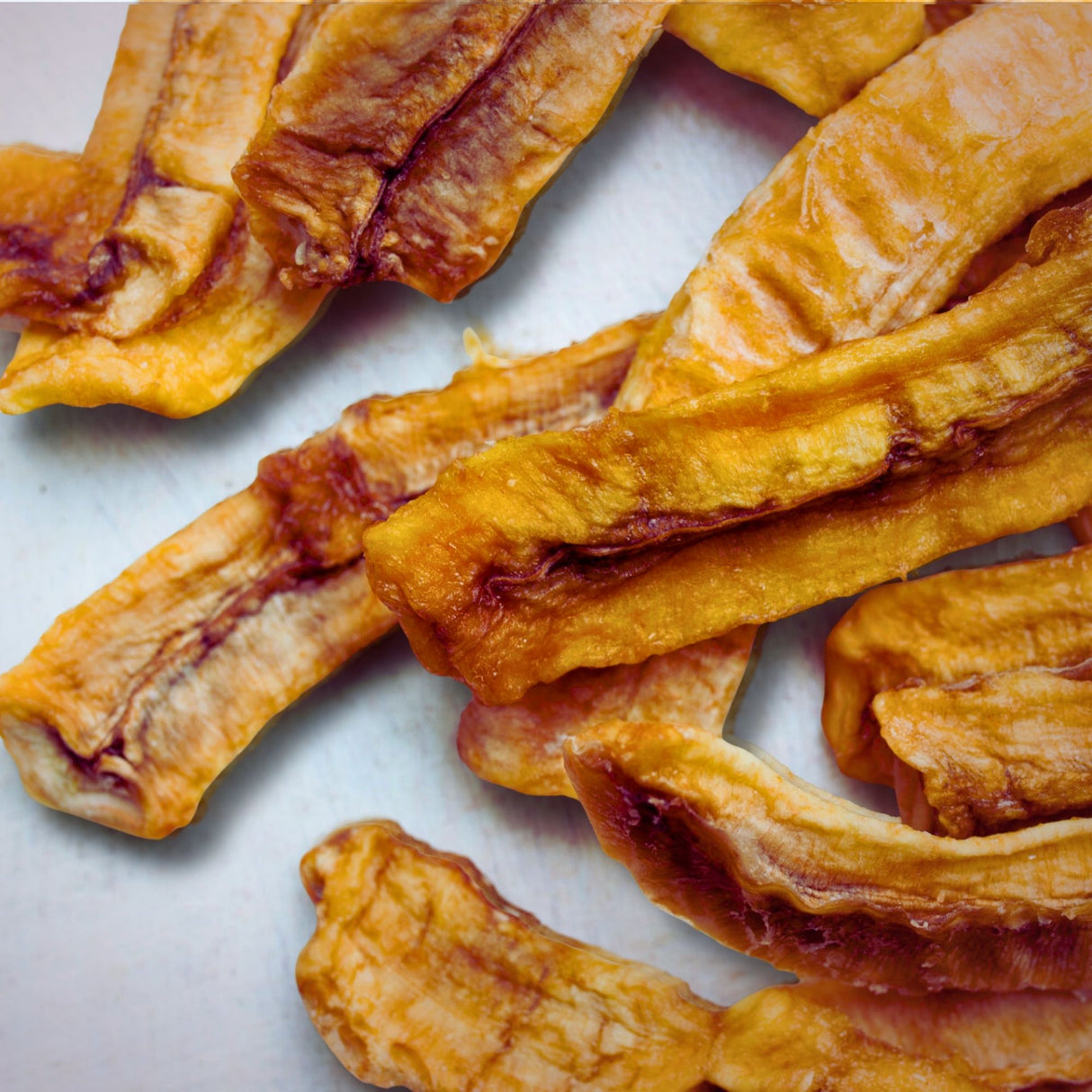 Close-up of Tropical Harvest dried banana slices dipped in lime juice showing natural caramelisation and citrus edge. 100% Australian fruit, no additives.
