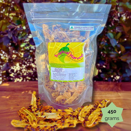 450g Tropical Harvest dried banana with passionfruit pulp resealable pack. Chewy banana strips with tangy passionfruit seeds are shown on a wooden background.