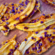Close-up of Tropical Harvest dried banana strips drizzled with real passionfruit pulp and seeds. Naturally chewy, tangy, and 100% Australian fruit.
