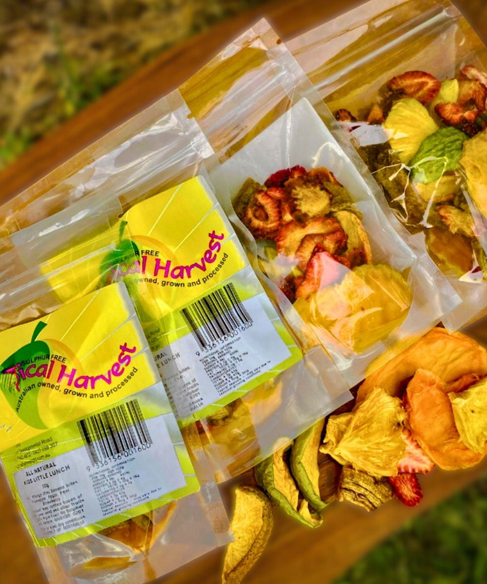 Tropical Harvest dried fruit blend snack packs with pineapple, strawberry, mango, and pear pieces displayed on a wooden board — all-natural, sulphite-free, healthy Australian snacks.