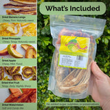 Hand holding Tropical Harvest dried fruit mix pouch with side panel listing included varieties: banana, pineapple, apple, kiwi, and watermelon. No sugar, sulphites, or preservatives.