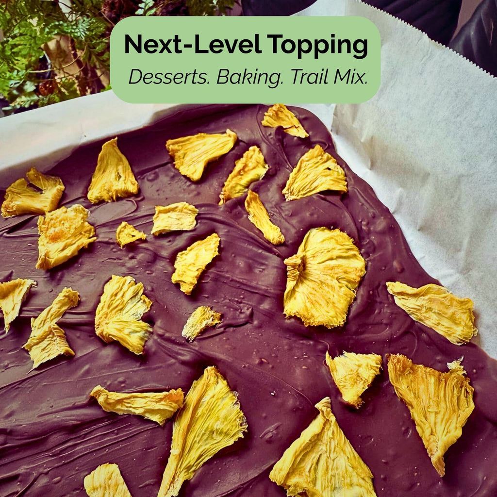 Tropical Harvest dried pineapple is used as a topping on chocolate bark. Text overlay: "Next-Level Topping: Desserts. Baking. Trail Mix."