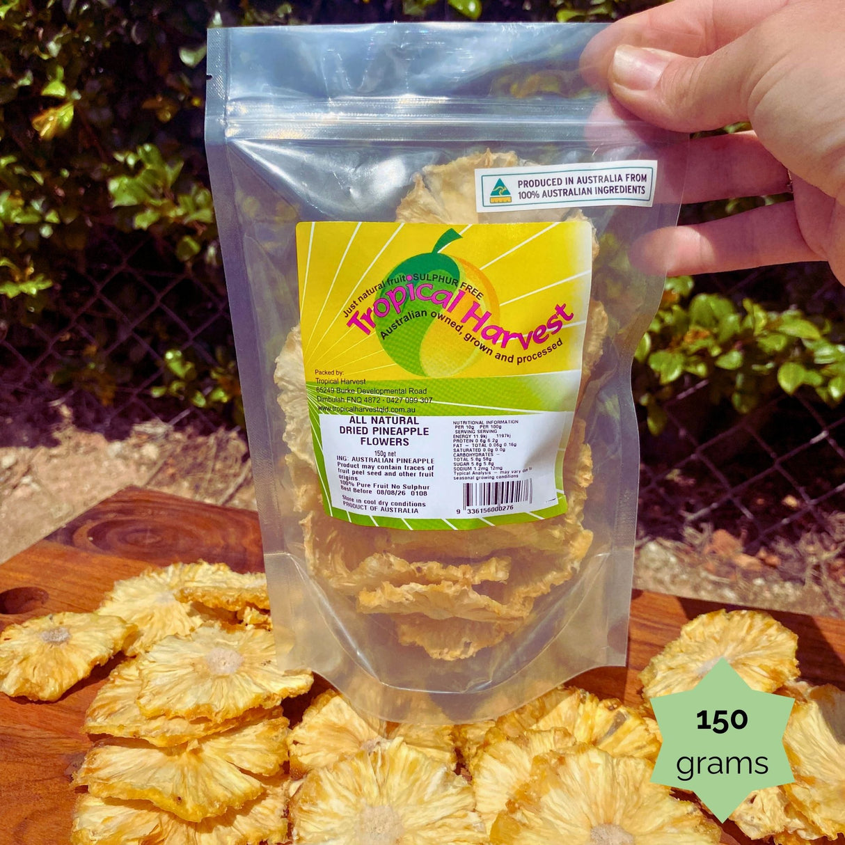150g resealable pouch of Tropical Harvest dried pineapple flowers with a starburst label. Perfect for snacking, gifting, or decorating cakes.
